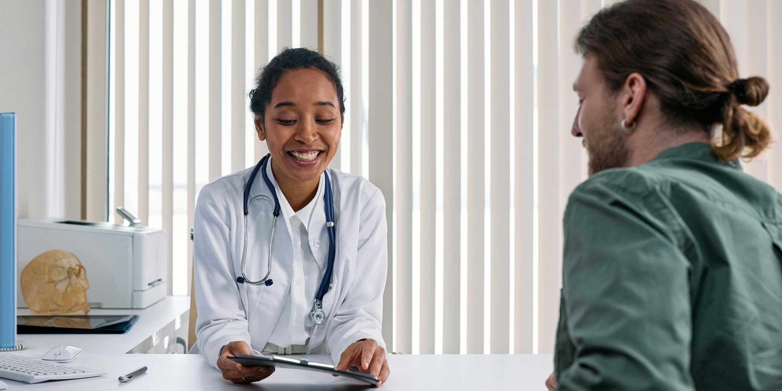 person talks to a medical professional sitting behind a desk