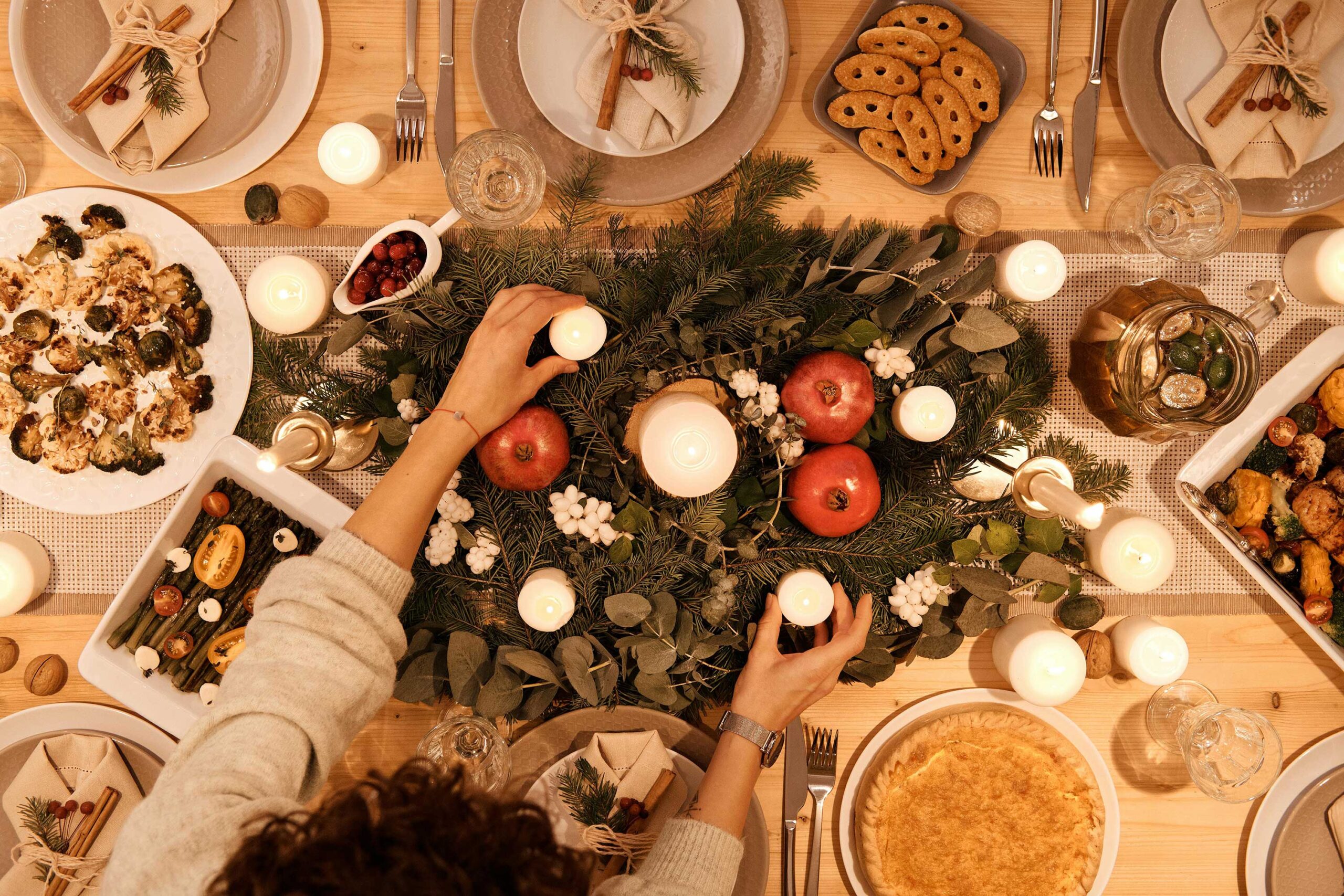 person sets candle on table of food decorated for the holidays